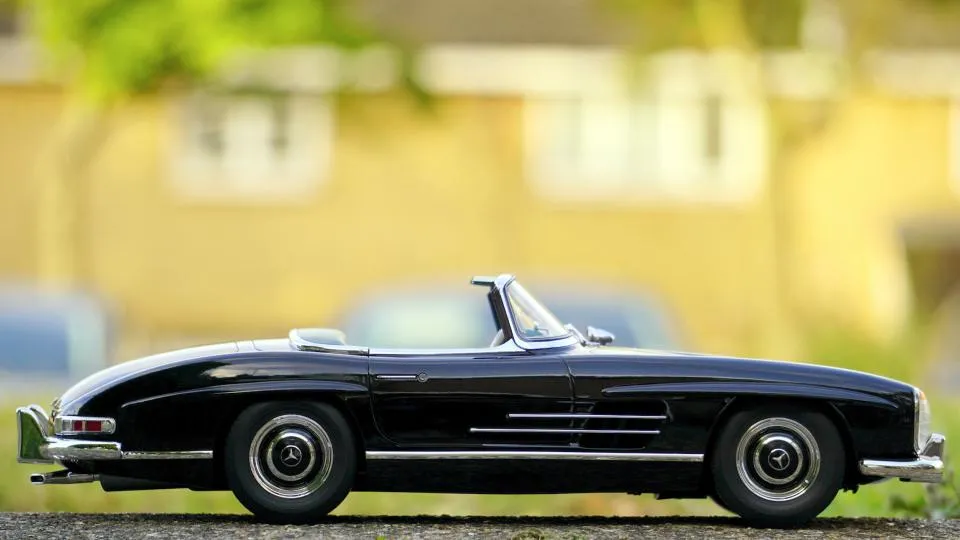 A classic black roadster in profile with deep, even black paint